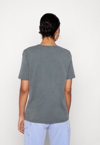 Harmaa lyhythihainen t-paita, jossa on pyöreä pääntie, valmistettu pehmeästä kankaasta. Takakuvassa näkyy rento istuvuus ja suora helma.