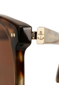 Aurinkolasit, joissa on kilpikonnakuosiset kehykset ja kultainen yksityiskohta, jossa on ankuri-kuvio sivuilla, sileä pinta ja pyöristetyt reunat.