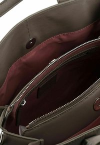 Interno di una borsa in pelle grigia con rivestimento bordeaux, dotato di una tasca con zip e un ulteriore scomparto con chiusura a scatto.