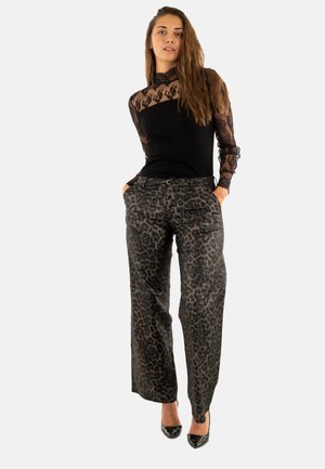 Top lungo a maniche nere in pizzo con dettagli trasparenti, abbinato a pantaloni larghi grigi con stampa leopardata realizzati in un tessuto liscio. Tacchi neri.