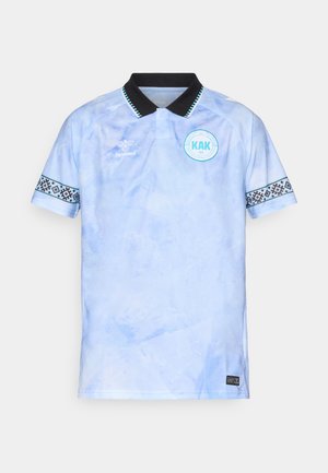 Lyseblå polo shirt med sort krave. Har mønstrede sorte detaljer på ærmerne og et rundt logo med "KAK" på brystet.