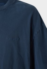Camiseta de manga corta de color azul oscuro, hecha de una tela suave y con cuello redondo. Incluye un sutil logo bordado de "Carhartt" en un color a juego.