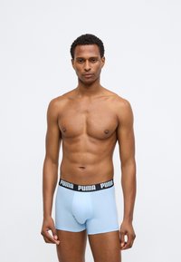 Svetlomodré boxer šortky vyrobené z mäkkej látky, s čiernym elastickým pásom s bielym potlačou loga "PUMA" a priliehavým strihom.
