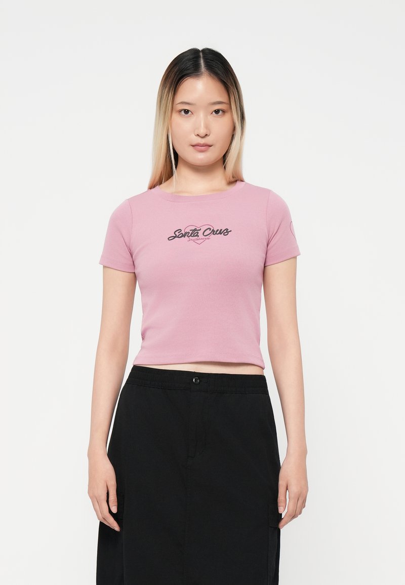 Tricou scurt roz, cropped, cu o grafică neagră "Santa Cruz" pe față, cu mâneci scurte și decolteu rotund.