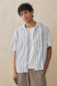 Short-sleeve, button-up shirt in light blue and white stripes. Made of a textured fabric, features a left chest pocket and relaxed fit.