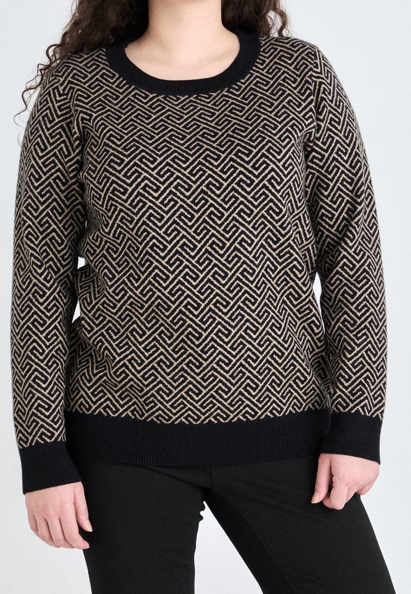 Pull noir et beige à motif, avec un col rond, un design en tricot texturé et des poignets côtelés. Associé à un pantalon noir.