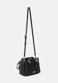 Black textured handbag with dual handles and a long adjustable strap, featuring gold hardware and a decorative scarf detail.