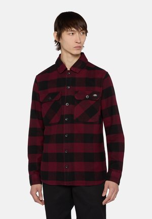 Rød og sort ternet flannel skjorte med krave, to brystlommer med klap og knaplukning. Fremstillet af struktureret stof.