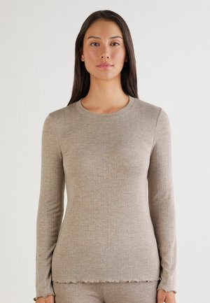 Haut beige à manches longues en tissu doux, avec une texture côtelée, un col rond et un ourlet en dentelle pour une coupe décontractée.