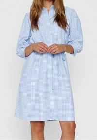 Abito camicia a scacchi blu e bianchi con bottone sul davanti, maniche lunghe, vita arricciata e orlo dritto. Tessuto dalla consistenza morbida.