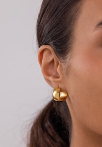 Boucles d'oreilles en or avec une finition polie et mate. Le design présente une forme fendue, mettant en avant des textures contrastées.