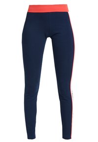 Mörkblå leggings med ett rött midjeband och en vit rand som är omgiven av rött som löper längs utsidan av varje ben.