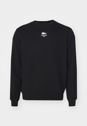 Zwarte lange mouwen trui met ronde hals, voorzien van een wit Lacoste-logo en de tekst "Lacoste Paris" gecentreerd vlakbij de kraag.