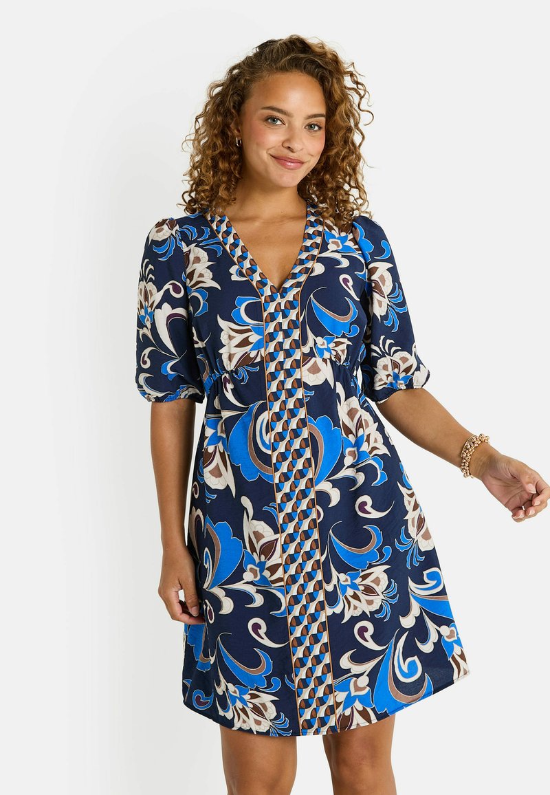 Vestido azul marino con estampado floral en azul, marrón y crema. Presenta un escote en V, mangas abullonadas y una cintura fruncida.