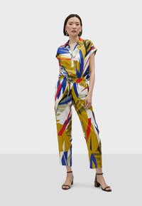 Tuta colorata con chiusura a bottoni sul davanti, maniche corte, motivi grafici in giallo, blu e rosso; vita con cintura, vestibilità comoda.
