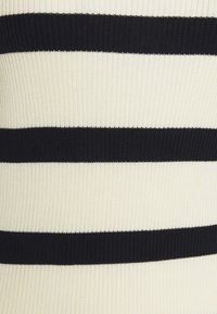 Tissu côtelé rayé en crème et noir. Présente de larges rayures horizontales avec un aspect texturé. Matériau doux avec élasticité.