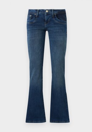 Kék farmer bootcut nadrág első zsebekkel és gombos záródással, egyszínű világosszürke háttér előtt bemutatva.