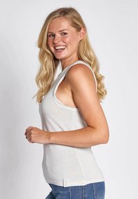 Light gray sleeveless top with a fitted design and scoop neckline, made of cotton. Features a subtle pattern on the front and a side slit.