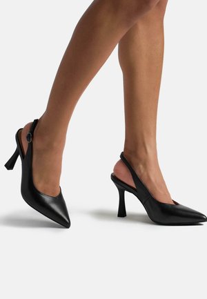 Décolleté slingback in pelle nera con punta affilata e tacco chunky. Presenta una cinghia con una fibbia circolare per una vestibilità regolabile.