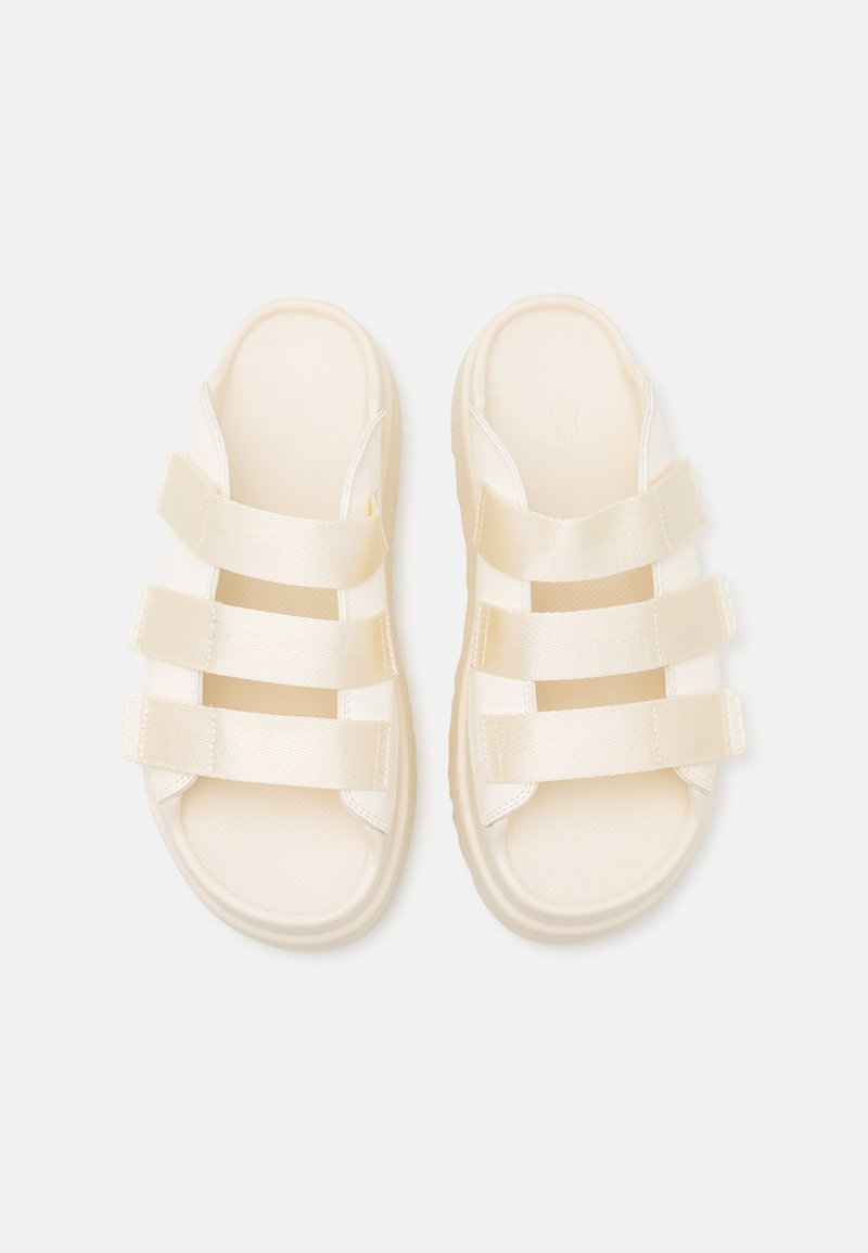 Crème-kleurige sandalen met drie brede stoffen banden, een textuur voetbed en een flexibele zool. Eenvoudig en modern ontwerp.