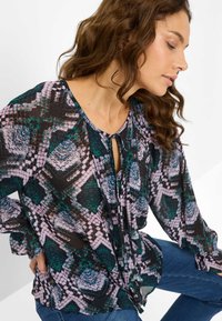 Multifarvet bluse med slangeprint i grøn, pink og sort, med en nøglehul-udskæring og lange, løse ærmer.