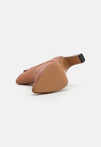 Brune lærhøye sko med rund tå og lav, firkantet hæl. Sålen har en teksturert, sklisikker design.