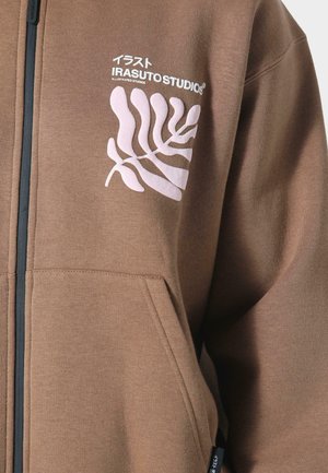 Brown zip-up hoodie made of soft fabric, featuring a white graphic with leaf design and brand logo on the chest, and front pockets.