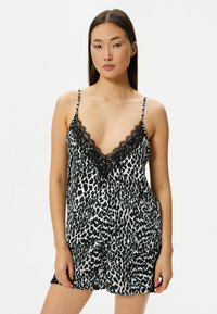Leopardmønster camisole i sort og hvid, glat stof, V-hals med sort blonder, tynde justerbare stropper, løs pasform.