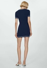 Abito corto blu navy con bordi bianchi, realizzato in materiale elastico. Presenta un design aderente e maniche corte, che termina sopra il ginocchio.