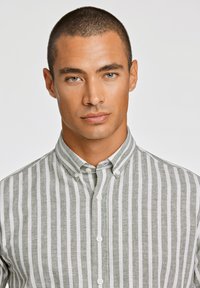 Button-up skjorte i grøn og hvid stribet mønster, med klassisk krave og frontknapper, lavet af letvægtsstof.