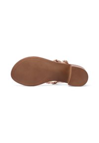 Sole di scarpa marrone chiaro con linee di grip testurizzate. Presenta un tacco basso e un design fluido, con una punta arrotondata e senza decorazioni visibili.