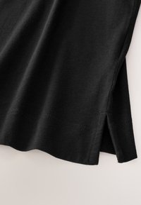 Czarny bawełniany t-shirt z okrągłym dekoltem i bocznymi rozcięciami na dole. Gładka faktura z starannymi detalami szwów.