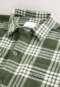 Groen-wit geruit flannel overhemd met een puntige kraag, drie knopen en een gestructureerde stof. Label zichtbaar bij de halslijn.