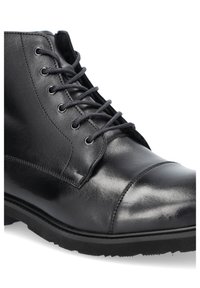 Czarne skórzane botki sięgające kostki z gładkim wykończeniem, okrągłym noskiem oraz metalowymi oczkami z czarnymi sznurowadłami; kauczukowa podeszwa z teksturowanym uchwytem.