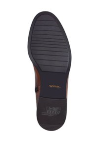 Semelle de chaussure en cuir marron avec des rainures horizontales et une surface texturée, présentant le logo "Ariat" en doré sur le côté.
