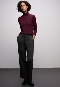 Burgundský rolák spárovaný se šedými širokými kalhotami se vzorem. Hladká textura s bočními kapsami, doplněné černými botami.