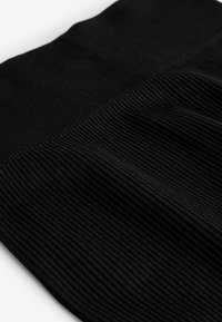 Tessuto nero a coste con texture orizzontale e dimensioni variabili. Il materiale appare morbido con leggere ondulazioni, creando profondità.