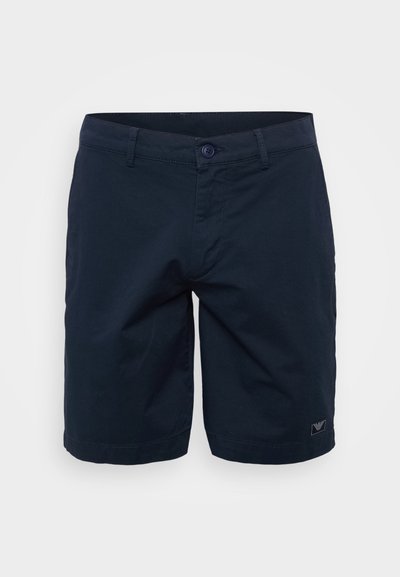 Pantaloni corte blu navy in tessuto di cotone, dotati di chiusura con bottone, passanti per cintura e una piccola etichetta logo sul lato sinistro.