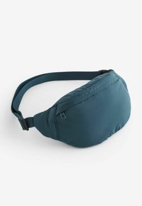 Pochette taille en teal, fabriquée en nylon doux, présentant une forme courbée, une poche zippée et une sangle réglable pour un ajustement sécurisé. Texture lisse et mate.