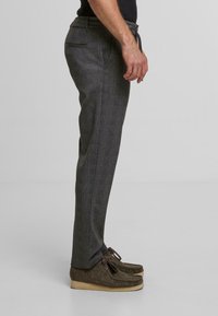 Gray patterned trousers with a slim fit, featuring side pockets and a drawstring waist, paired with brown textured moccasin shoes.