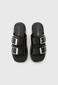 Sandali neri modello slide con due ampie fascette lucide decorate da fibbie argentate. Suola imbottita e interno liscio con finitura opaca.