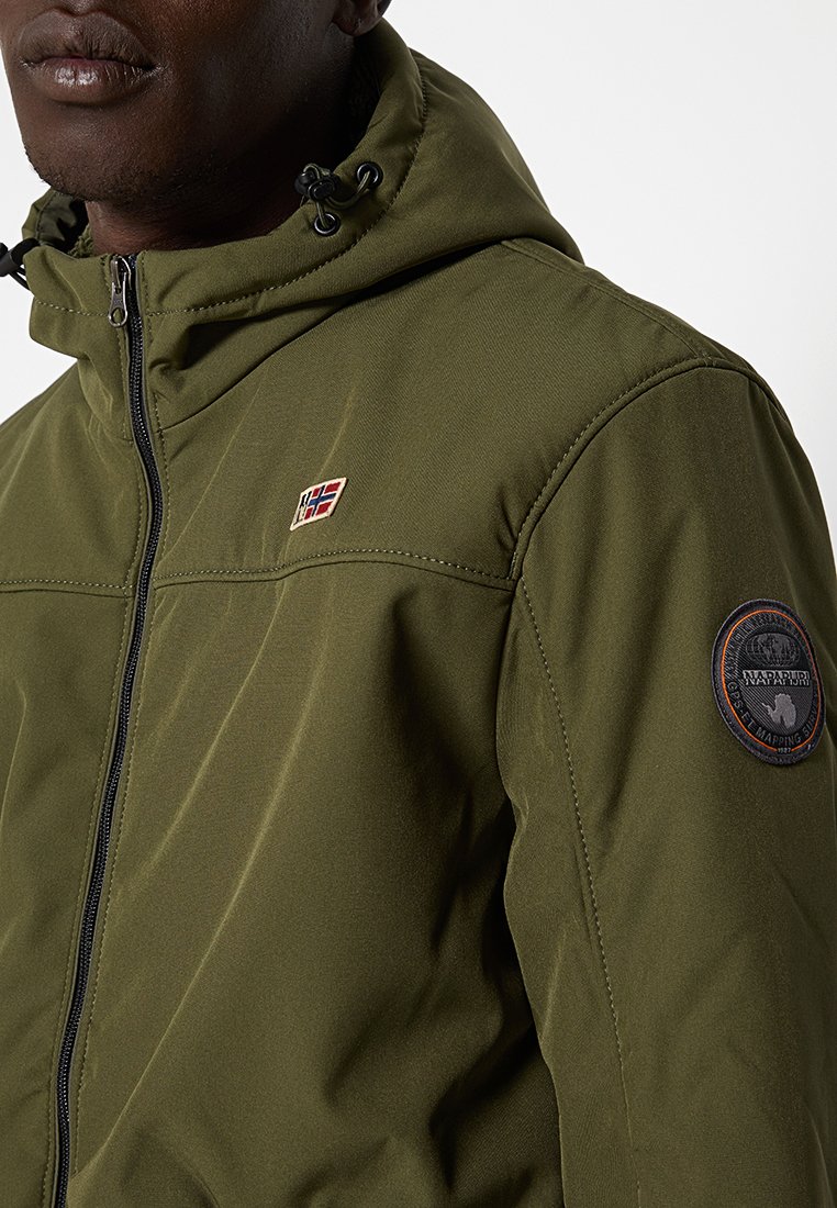 Chaqueta verde oliva con cremallera y capucha, que presenta un logo en el pecho y un parche redondo en la manga, confeccionada en tela suave y duradera.