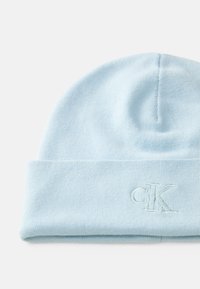 Lichtblauwe gebreide beanie met een omgeslagde rand en geborduurd "cK" logo aan de voorkant, getoond op een witte achtergrond.