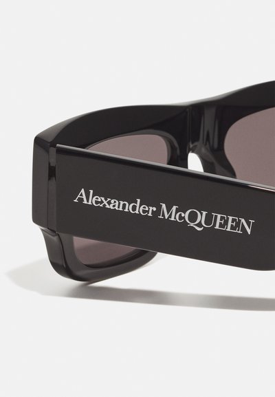Mustad mustad koos paksu ruudukujulise raami ja tumepruunide läätsedega. Templi peal on hõbedaste tähtedega "Alexander McQueen" logo.