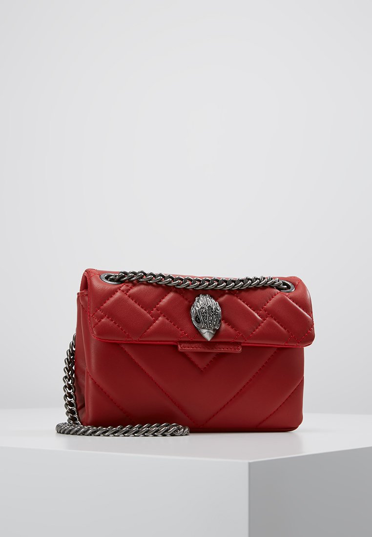 Czerwona pikowana skórzana torebka z srebrnym łańcuchem i dekoracyjnym zapięciem przypominającym szyszki. Kompaktowy prostokątny kształt.