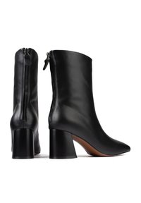 Bottes en cuir noir à la cheville, au design épuré, avec un bout pointu et un talon épais. Elles sont dotées d'une fermeture éclair à l'arrière pour un enfilage facile.