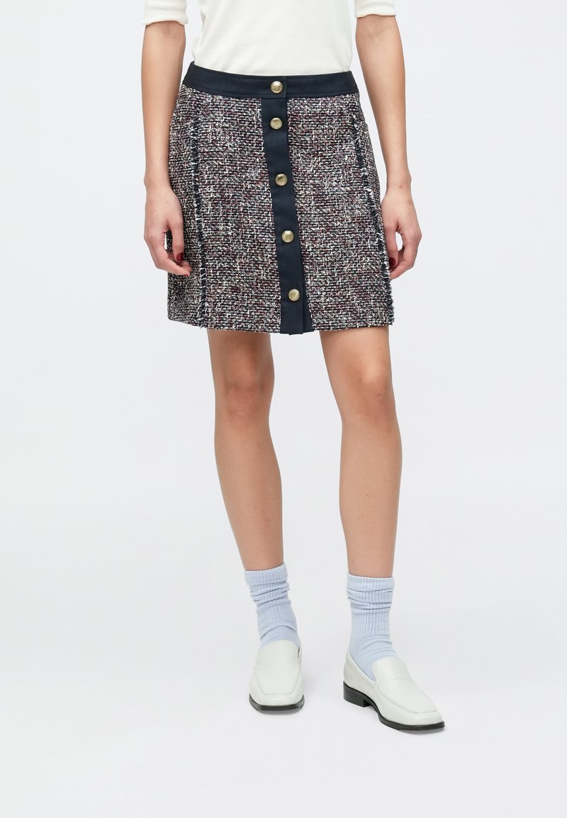 Tvidu mini svārki ar daudzkrāsainu faktūras rakstu, ar tumši zilu jostasvietu un zelta pogām priekšpusē.