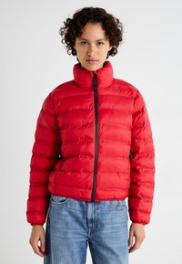 Rode windjack met hoge kraag, gequilt ontwerp, rits aan de voorkant en zwarte accenten. Draagt met spijkerbroeken met een ontspannen pasvorm.