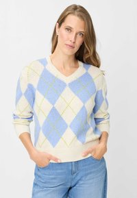 Maglione scollo a V in crema, con motivo a rombi blu e verdi. Tessuto a maglia, maniche lunghe, vestibilità comoda e orlo a coste con tasche laterali.