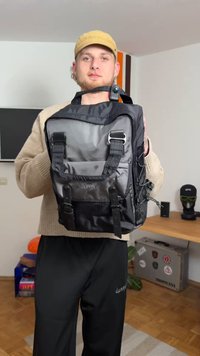 Black nylon backpack with multiple straps, metallic accents, and a textured surface. Features a spacious design and adjustable side cords.